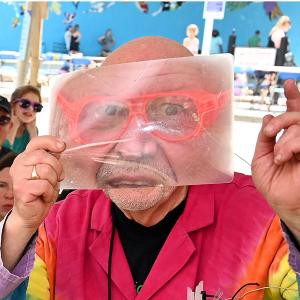 photo of scientist in tie-dye lab coat and face distorted by a magnifying sheet